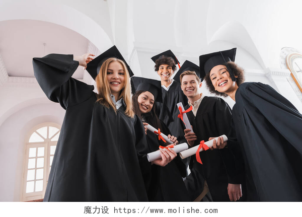 五个毕业生在拍照持文凭的多民族毕业生对着镜头微笑的低视角 